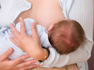 A mother breastfeeding her baby in a cozy setting.
