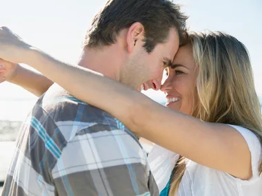 A couple embracing and smiling at each other on a sunny day.