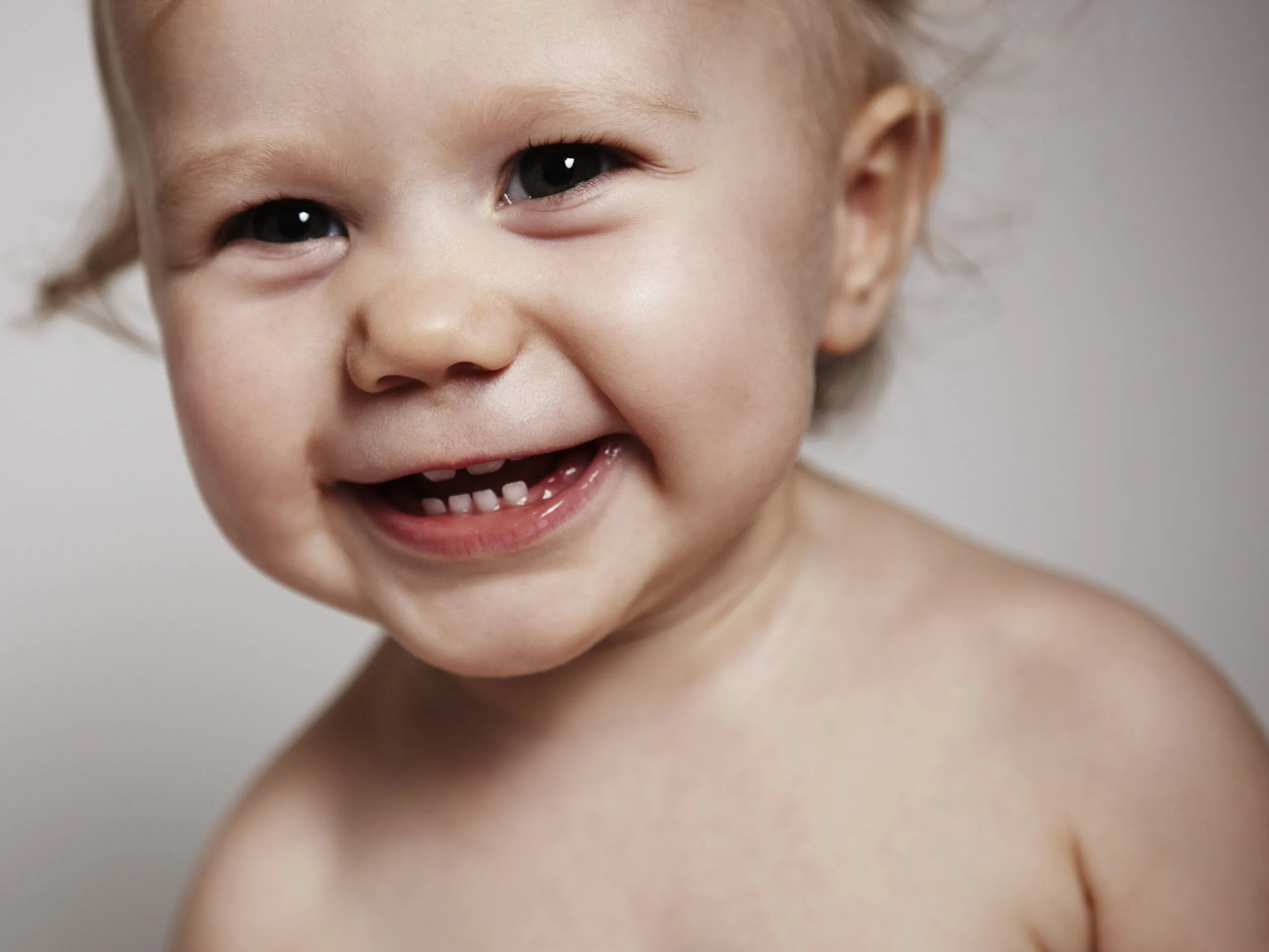 Smiling baby with visible teeth, close-up shot.