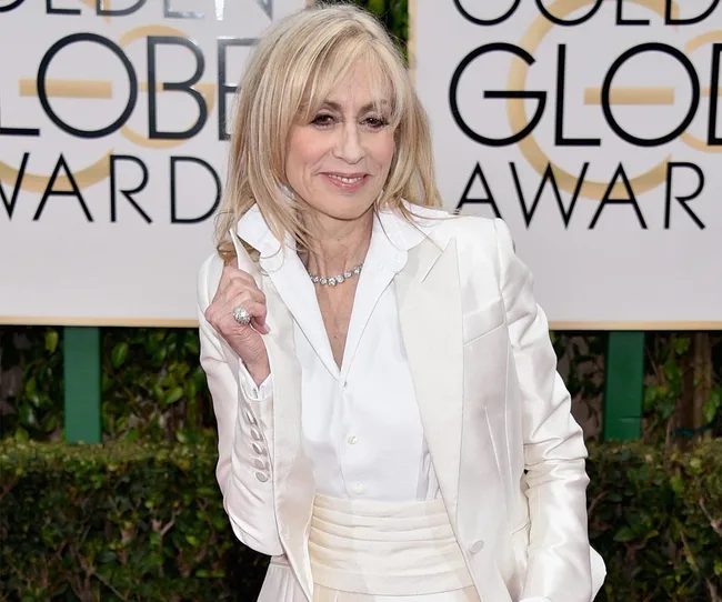 A woman in a white suit poses at the Golden Globe Awards.