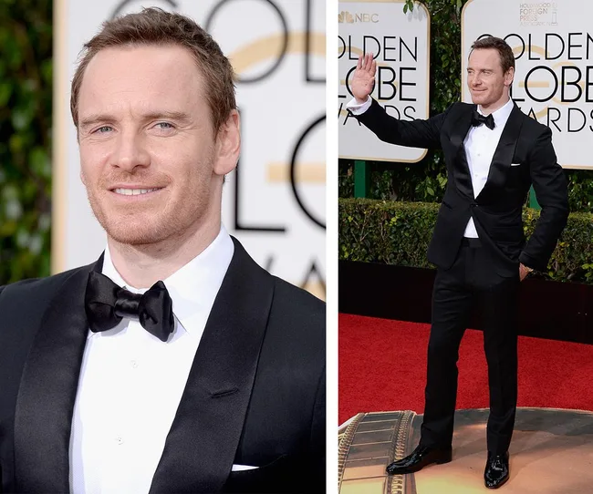 Man in black tuxedo at Golden Globe Awards, smiling and waving on the red carpet.