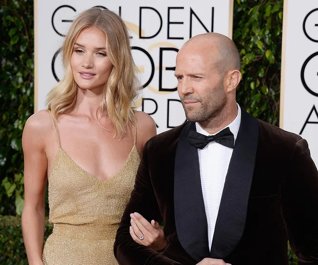A couple poses together on the red carpet at a formal event.