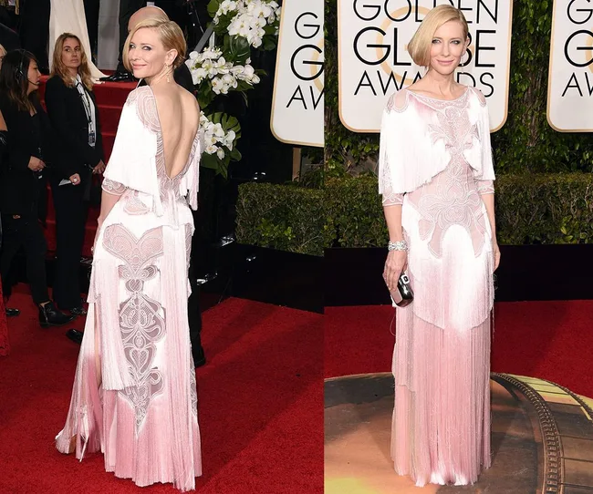 A woman in a pink, intricately designed gown on the red carpet at an awards event.