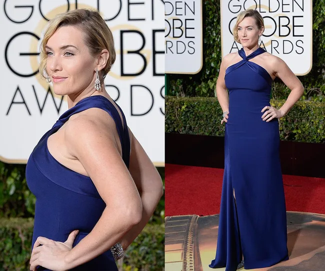 A woman in a blue halter gown poses at the Golden Globe Awards, with a garden and award signage in the background.