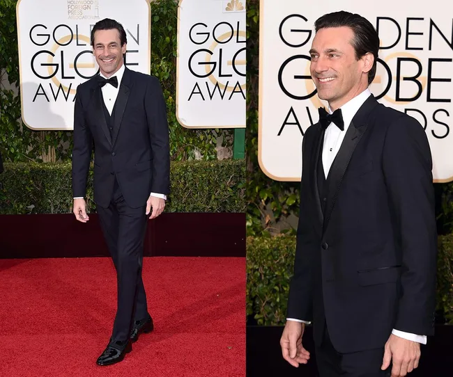 Man in a tuxedo on the red carpet at the Golden Globe Awards, smiling for photos.