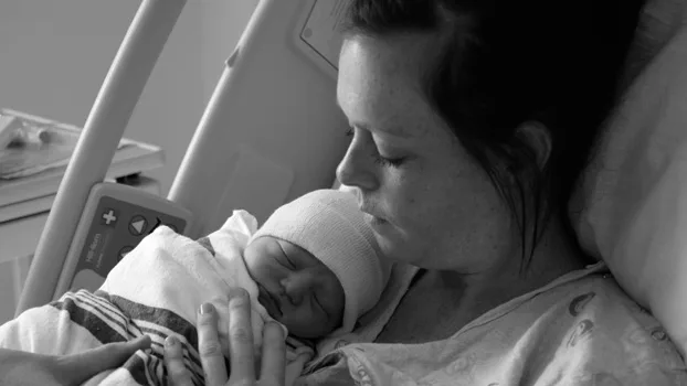 Mother tenderly holding her newborn baby in a hospital bed.