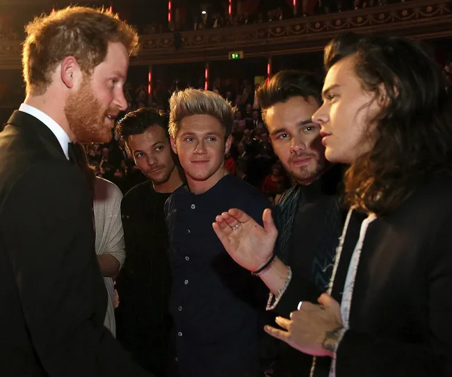 Group of young men talking to a man in a suit at a public event.
