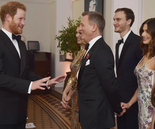 A group of people in formal attire smiling and talking at an indoor event.