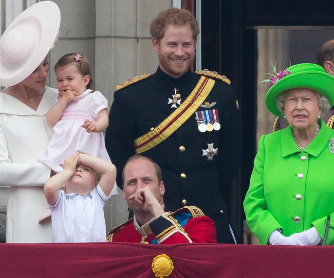 Individuals on a balcony, one in a bright green outfit, others dressed in formal attire, with children present.