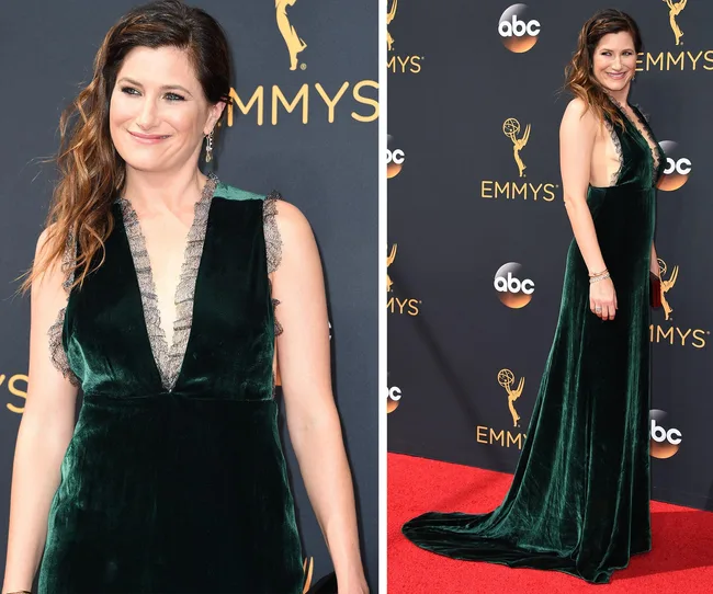Woman in a dark green velvet dress on the red carpet at the Emmys, posing for photos with a smile.