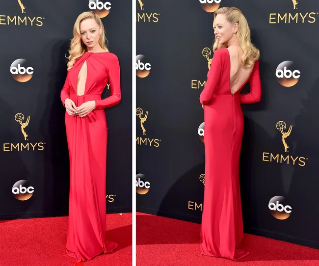 Woman in a long, red dress with cutout detail on the red carpet at the Emmys, posing from front and back.