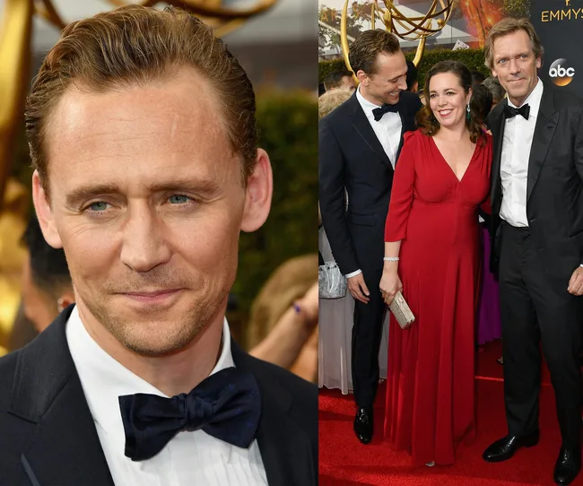 Three people in formal attire on a red carpet; two men in tuxedos and a woman in a red dress smiling.