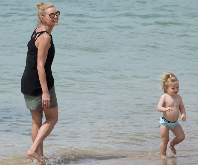 Adult and child playing near the water at a beach, with smiles and splashes.