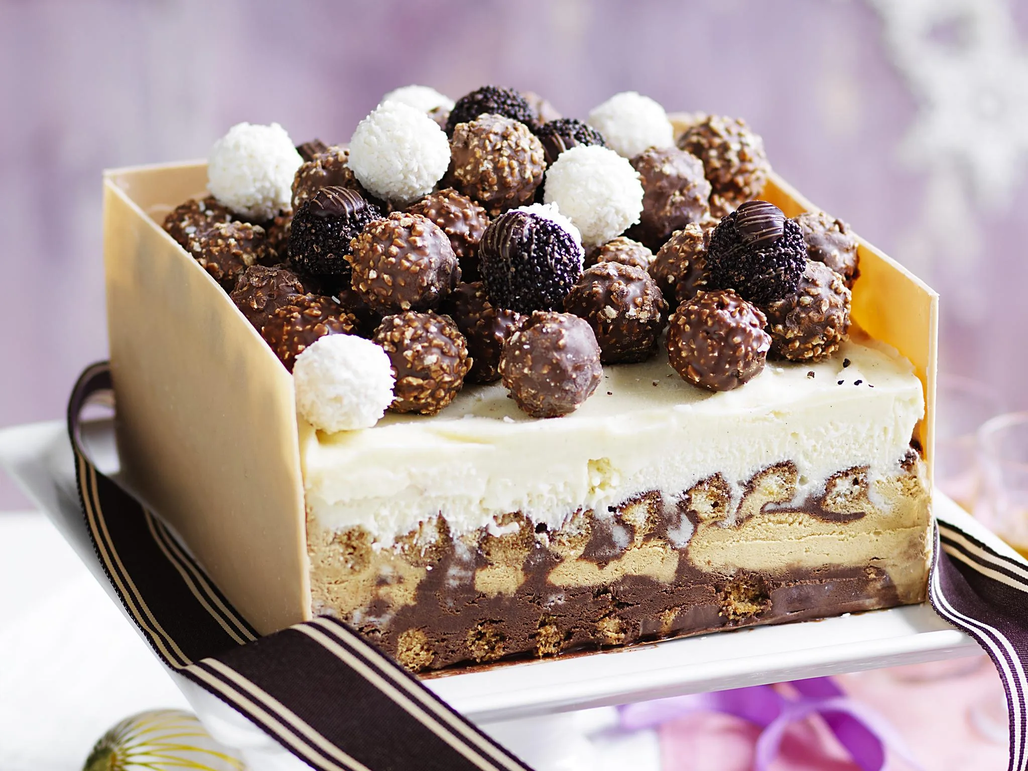 Festive layered Christmas cake topped with assorted chocolate truffles and wrapped with a ribbon.