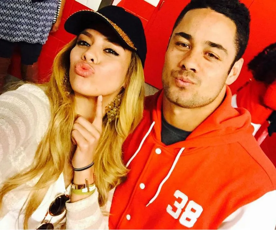 Two people taking a selfie, both making duck faces. One wears a cap, the other a red jacket with number 38.