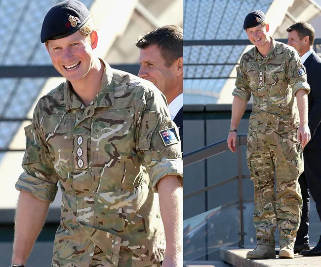 Soldier in camouflage uniform and beret walking outside with two men in suits.