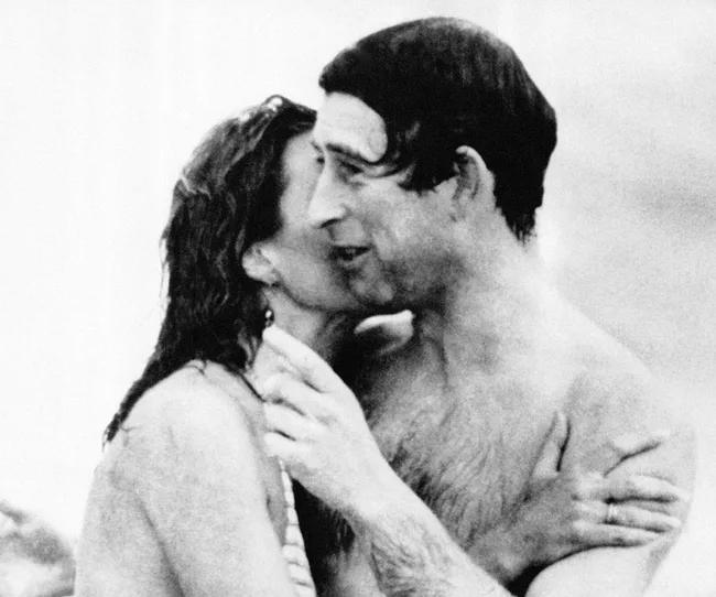 A black and white image of a man and woman embracing and smiling at each other, both in swimwear.