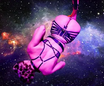 Woman in strappy harness suspended in space-themed background.