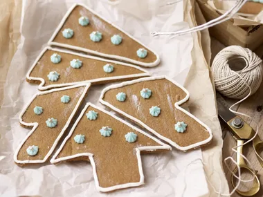 Gingerbread cookies arranged into a tree shape, decorated with white icing and blue frosting dots.