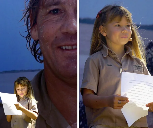 Young girl in Australia Zoo uniform speaks at an event, holding papers, in front of a large image of a man's face.