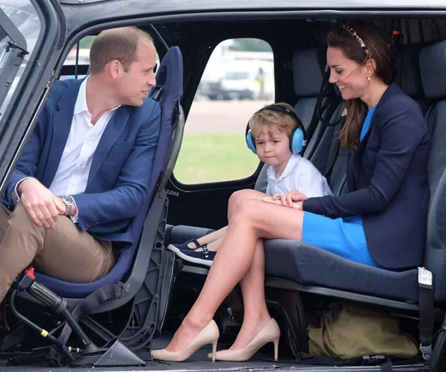 Family sitting inside a helicopter, child wearing blue earmuffs, adults smiling and interacting with the child.