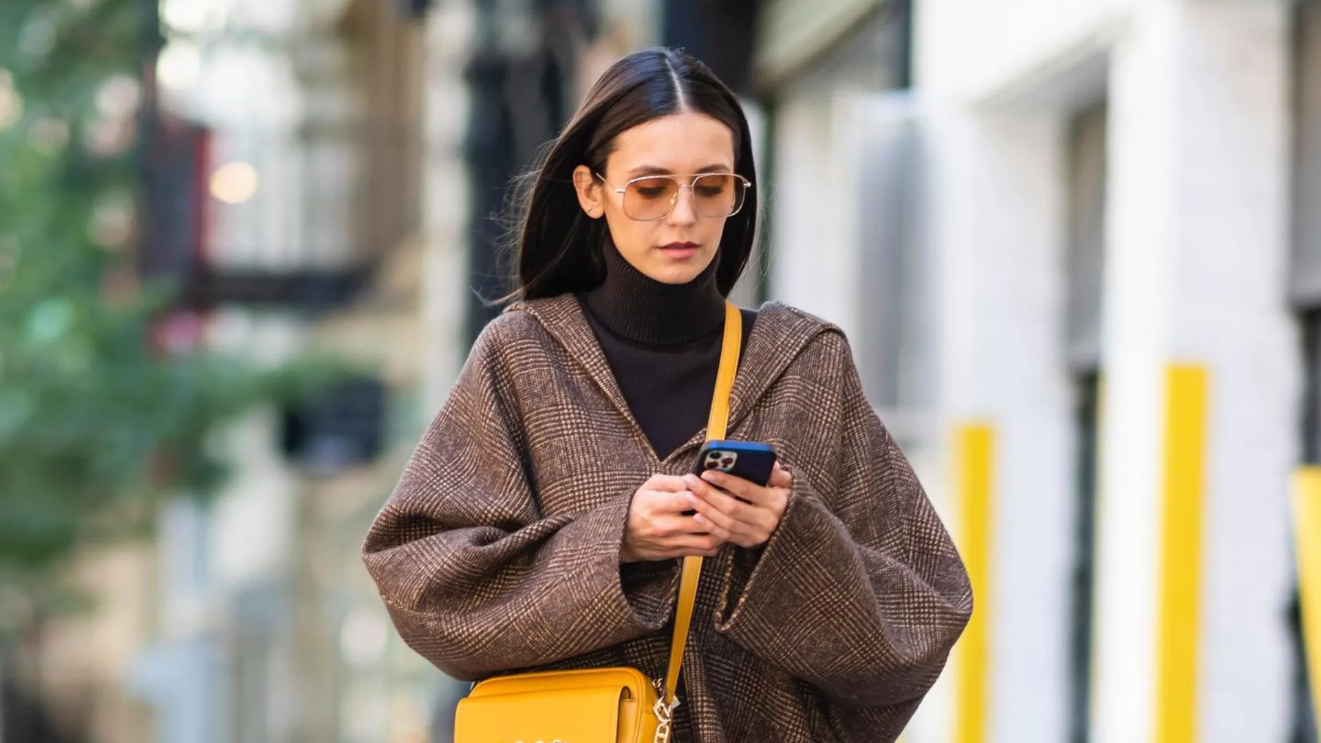 Woman walking and checking her phone, likely searching for Black Friday discounts.