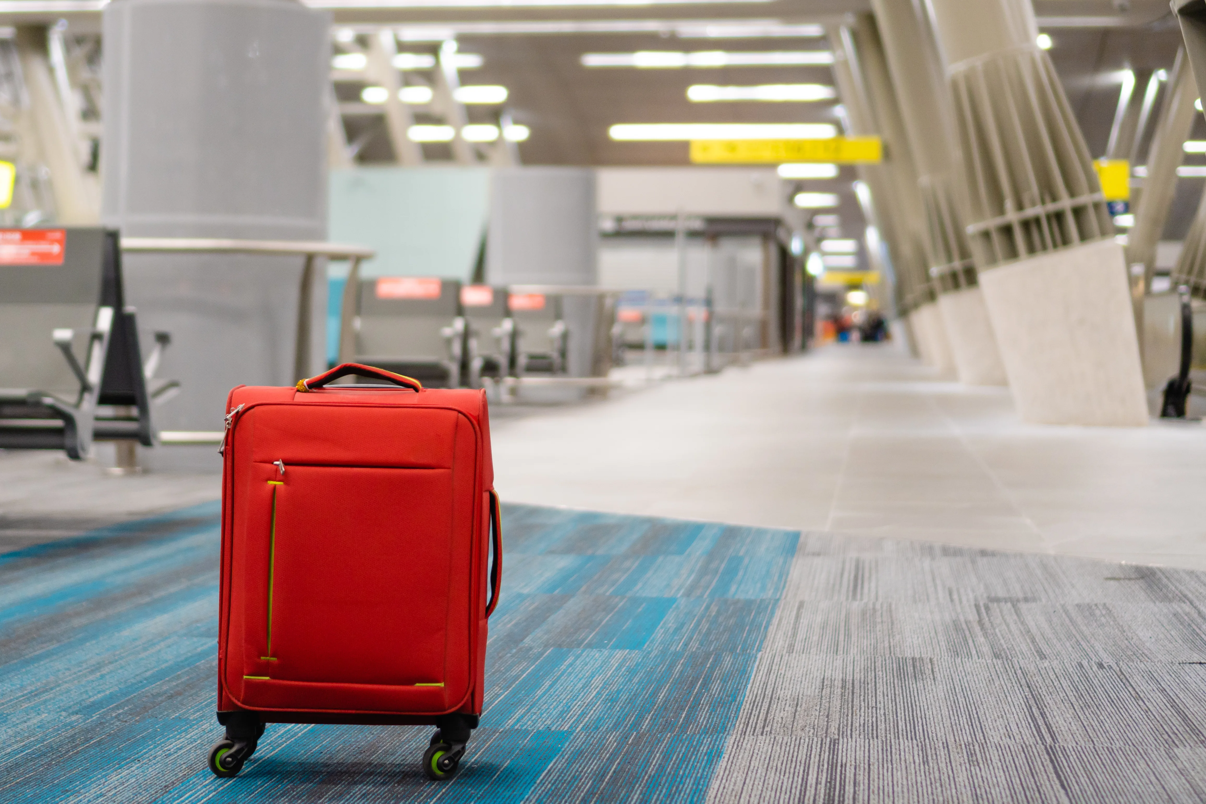 red wheeled carry-on suitcase, lost at the airport.