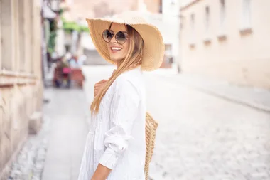 Young beautiful happy woman on vacation wearing summer hat and fashionable sunglasses.