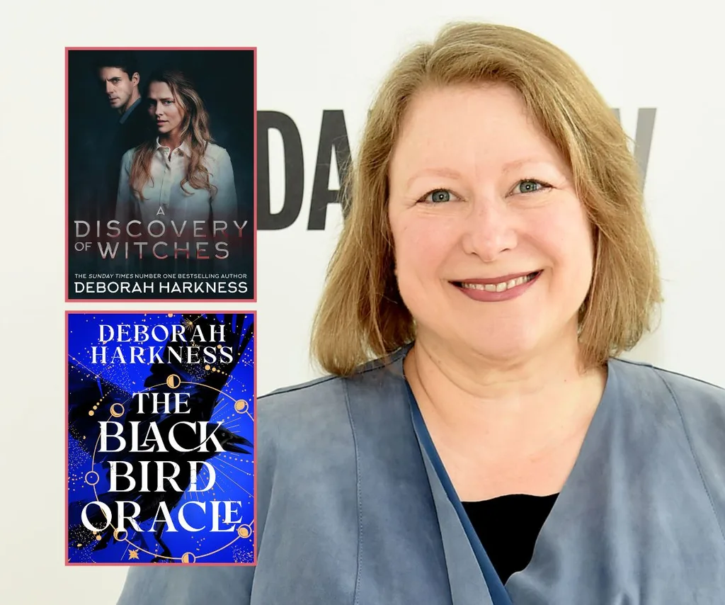 Author Deborah Harkness smiles wearing blue with her two books The Black Bird Oracle and A Discovery of Witches