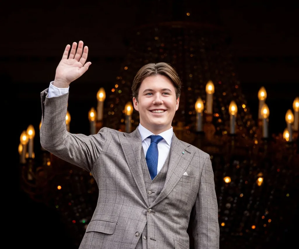 Danish Prince Christian smiles and waves wearing a suit with blue tie