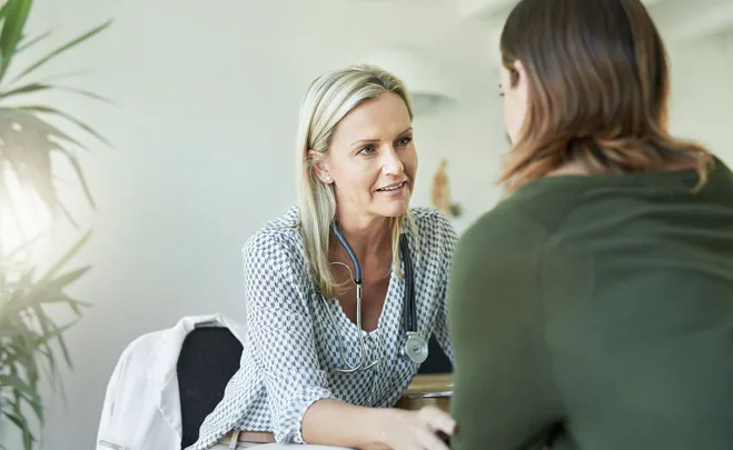 female doctor talks to woman patient sitting down