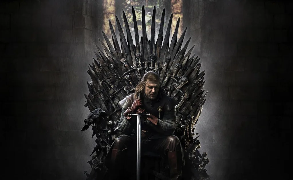 Game of Thrones Lord Eddard Stark, head of House Stark, sits on the Iron Throne, looking down with both hands on his sword, which is point down on the floor