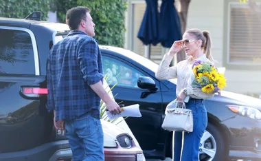 Ben and JLo, holding sunflowers, seen talking in front of cars