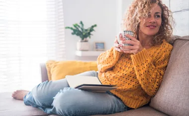 Woman reading book with cup of tea.