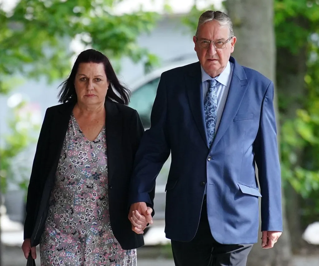 Parents Susan and John hold hands somber faced