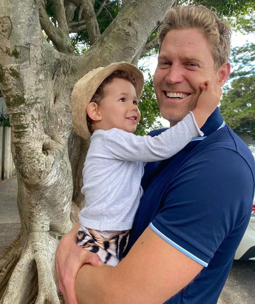 Dr Chris smiling, holding a small child