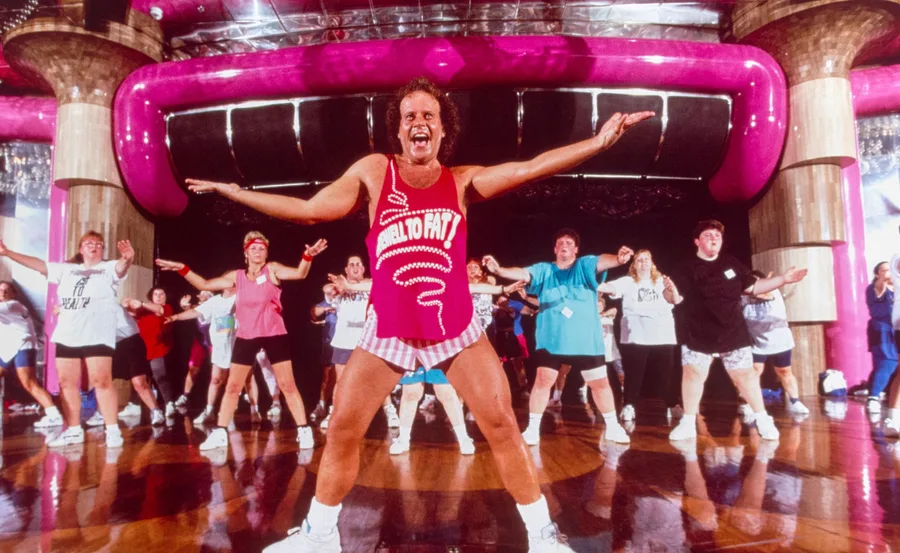 Richard Simmons leading a class in hot pink top and white tiny shorts