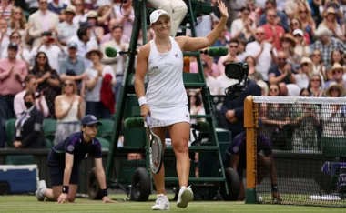 ash barty waves on a tennis court