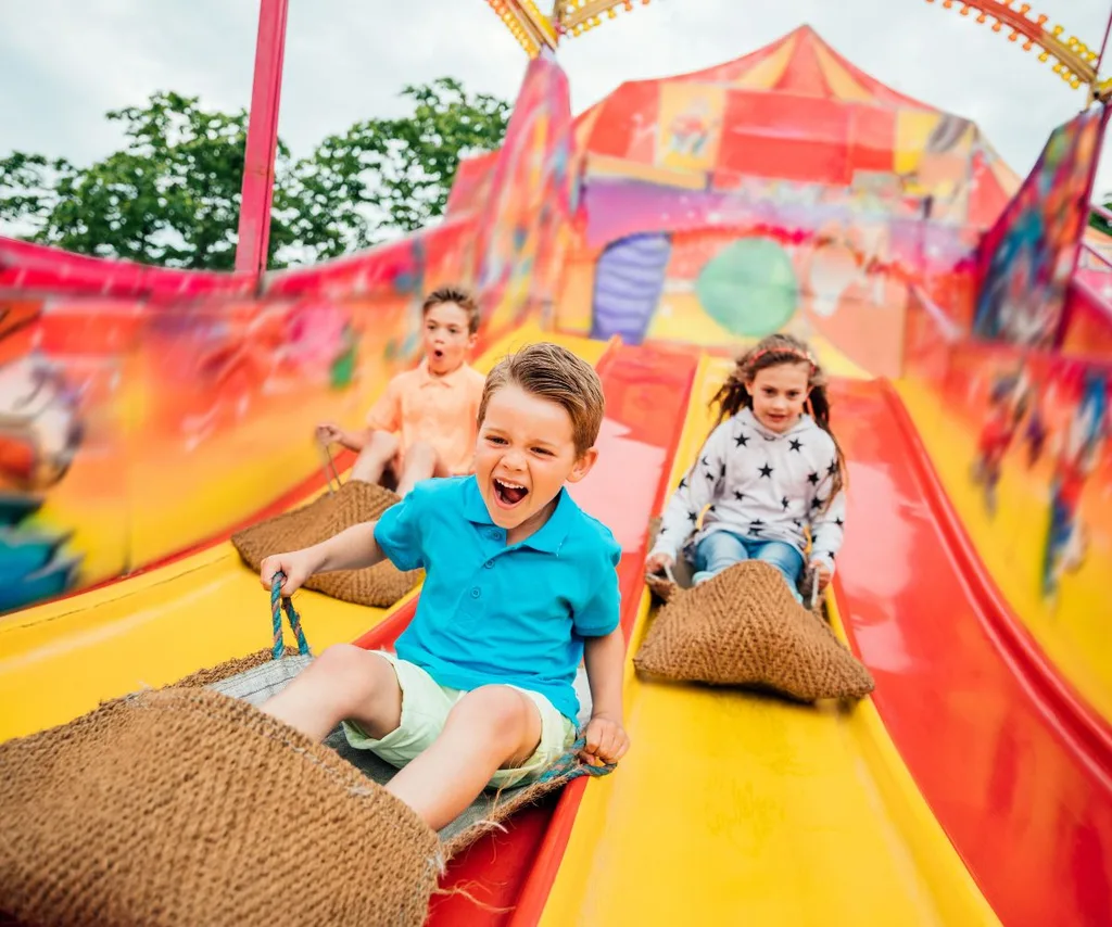 kids sliding down a big brightly coloured slide at a fair