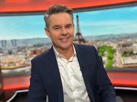 Todd Woodbridge sits at his commentators desk for the Paris Olympics with the Eiffel Tower in the backdrop