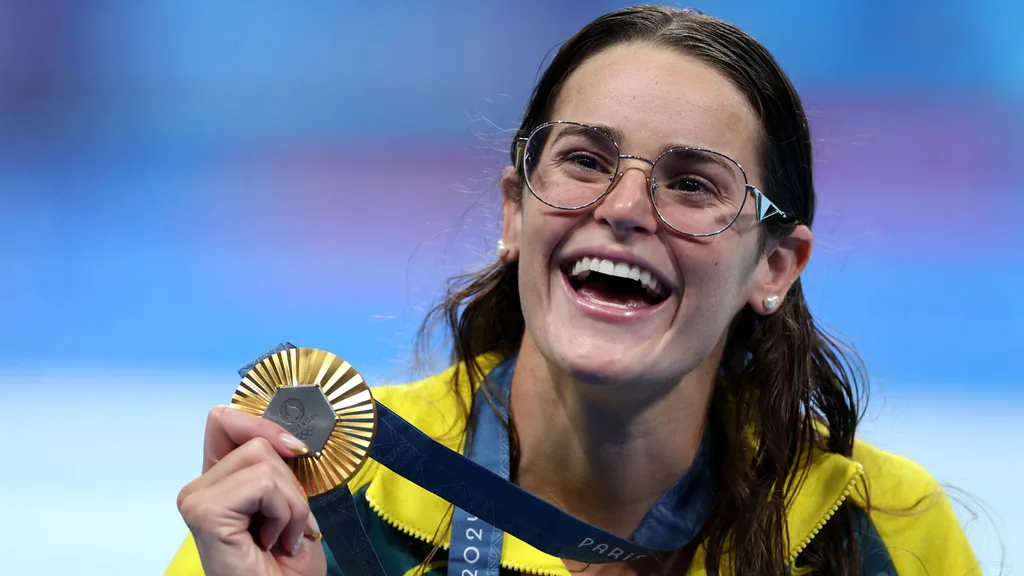 Kaylee McKeown beams holding her Olympic Gold medal for the 100m backstroke