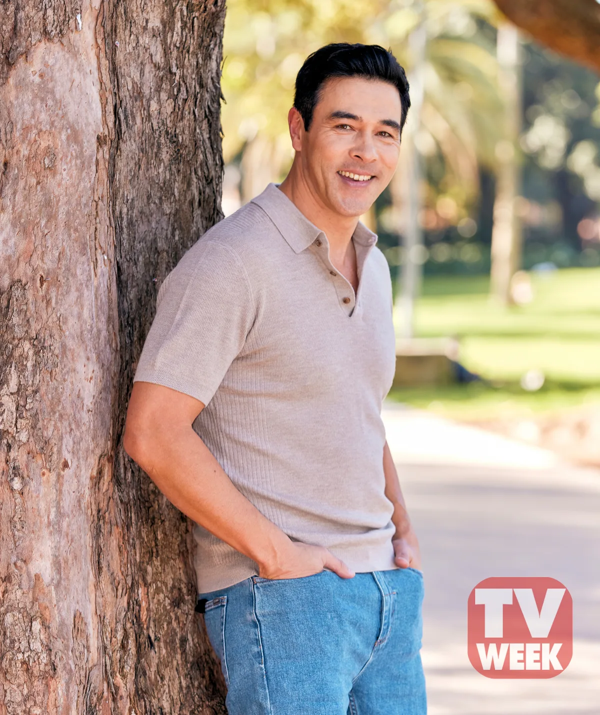 James Stewart smiles as he leans on a tree in a beautiful green park for his TV WEEK photoshoot.