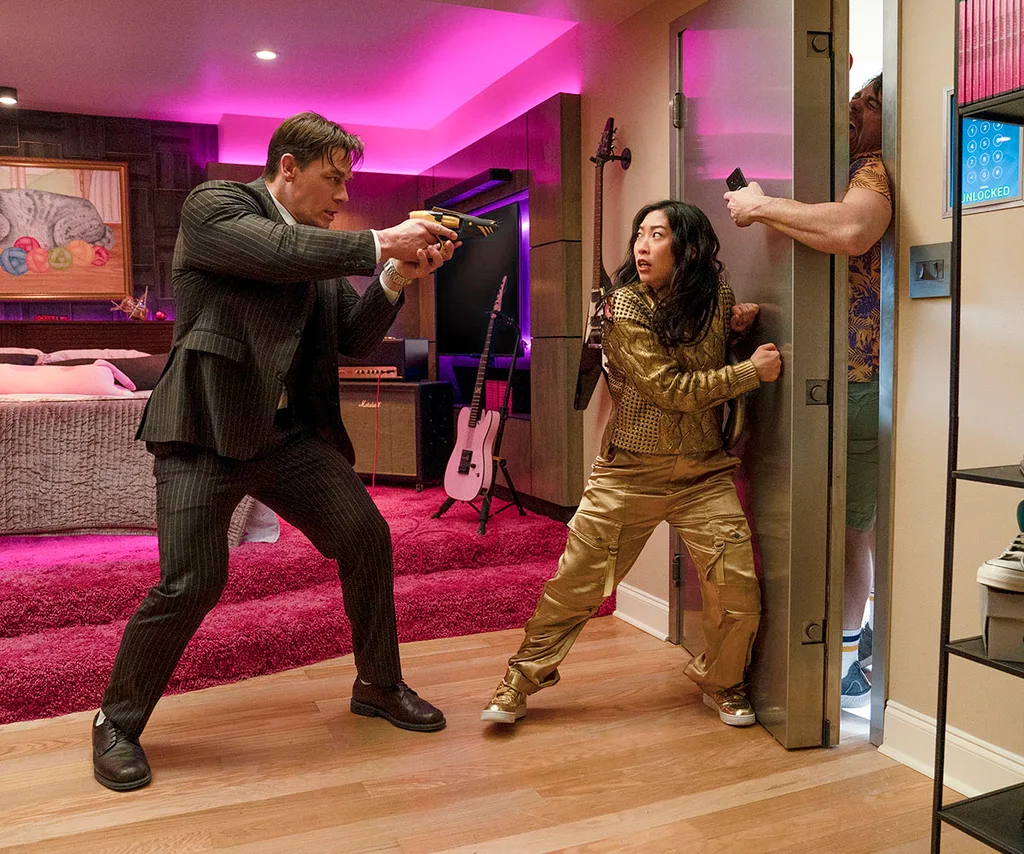 Noel Cassidy (John Cena) raises a gun to protect Katie Kim (Awkwafina) who has just won The Grand Lottery prize.