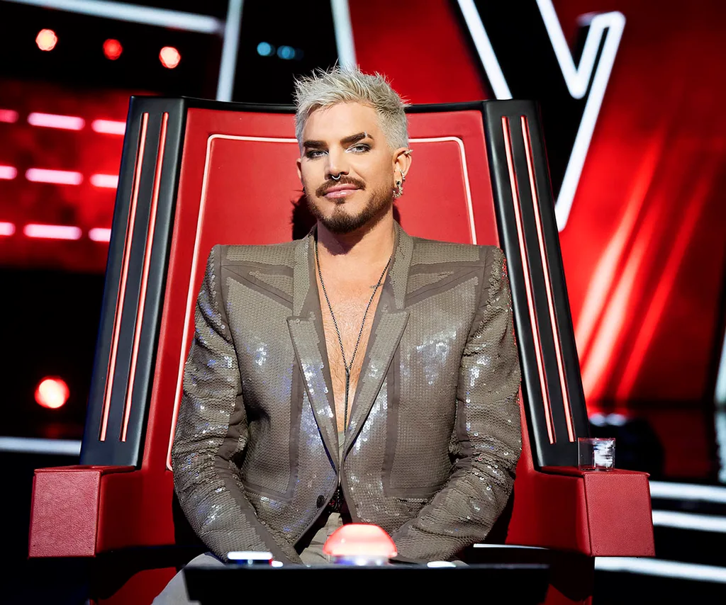 Adam Lambert sits in The Voice's iconic red chair.