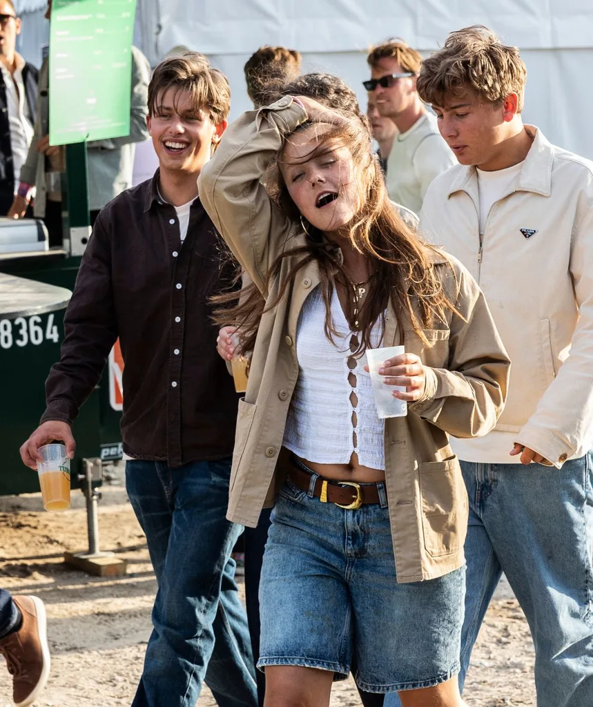 Danish Princess Isabella at a festival, arm up, eyes closed, holding a drink in her hand