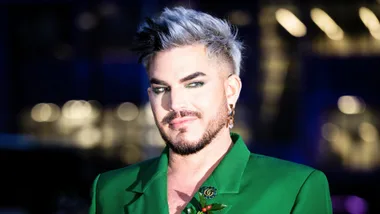 The Voice coach Adam Lambert wears green and eye liner, smirks