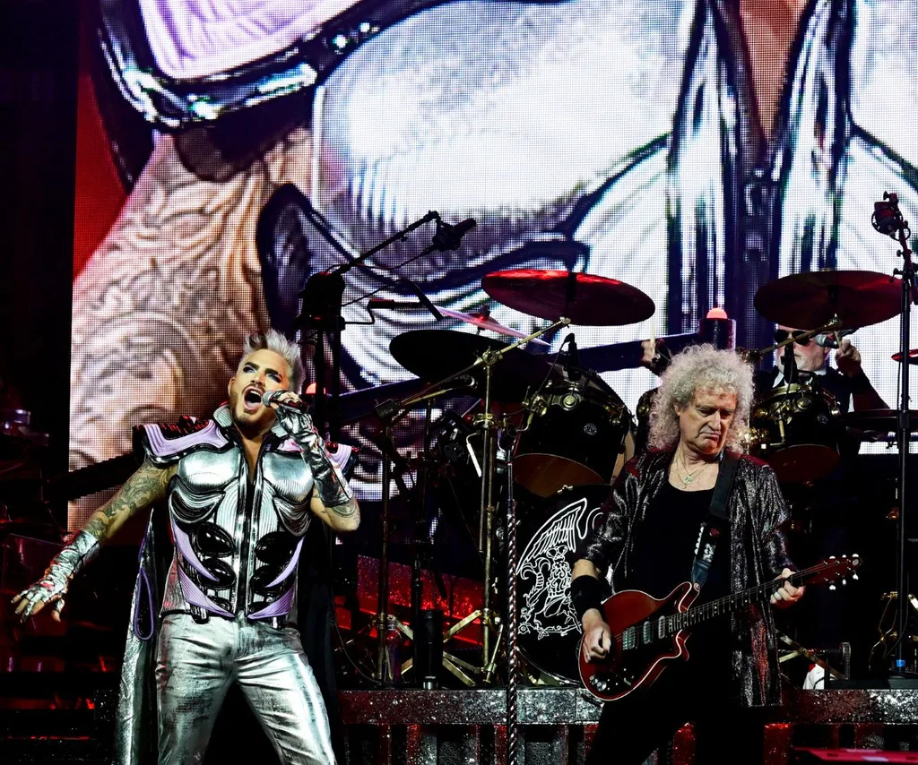 Adam Lambert on stage performing in silver as Queen's lead vocalist