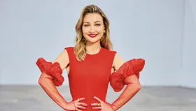 The Voice coach Kate Miller Heidke smiles in a red dress with hands on hips