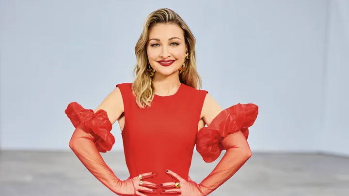 The Voice coach Kate Miller Heidke smiles in a red dress with hands on hips