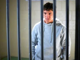 Perri (Cantona Stewart) stands behind bars as he faces prison for killing his father.